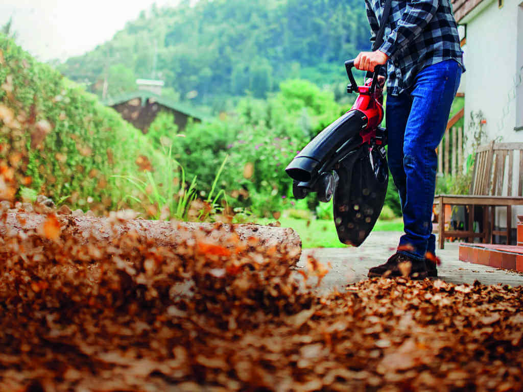 A man using a leaf vacuum. 
