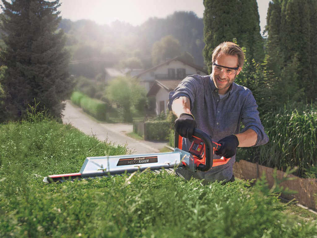 A man trimming the hedge.