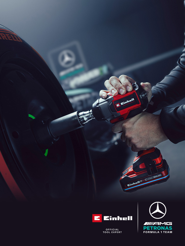 Llave de impacto inalámbrica Einhell en uso sobre una rueda de coche, con el branding y el logotipo de colaboración del equipo Mercedes-AMG Petronas de Fórmula 1