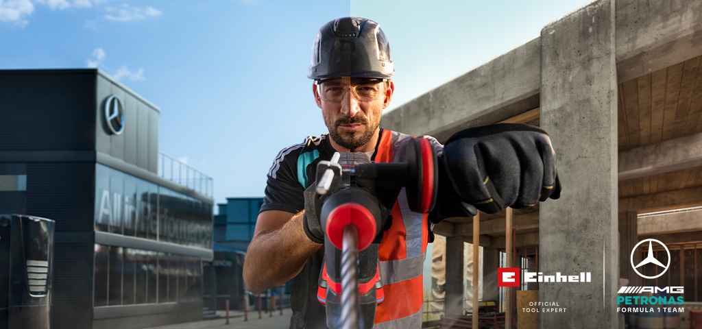 Un mecánico con equipo de protección taladrando con una herramienta eléctrica en una obra.