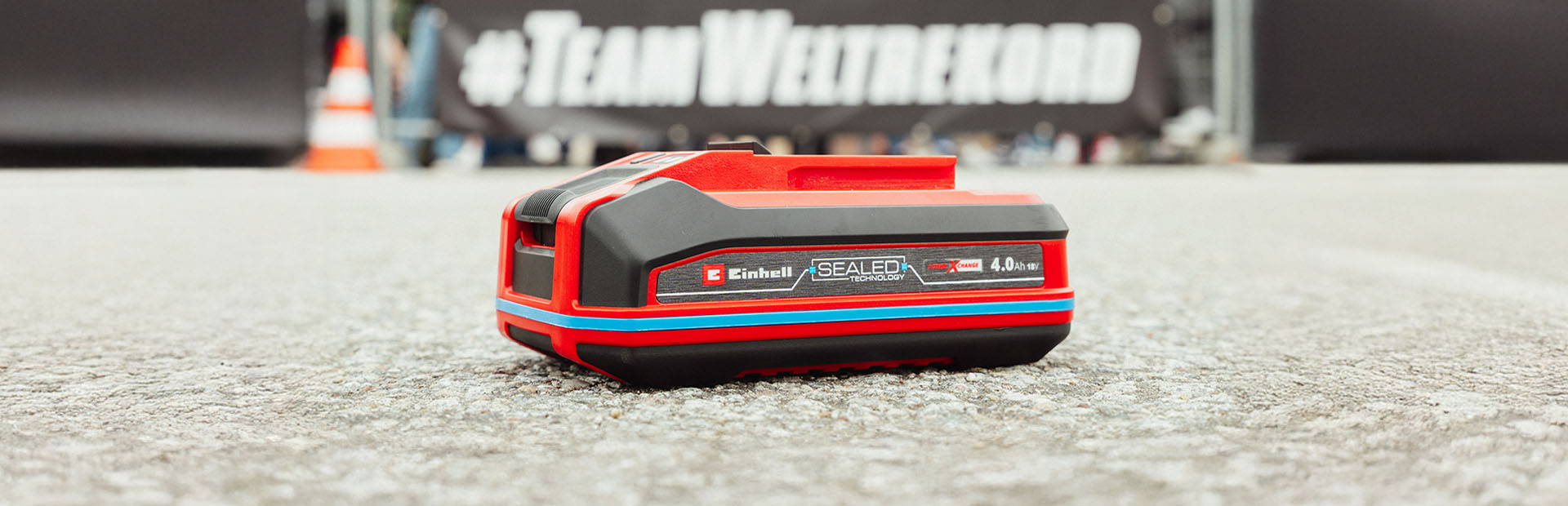 Einhell Power X-Change 4.0 Ah SEALED battery displayed in front of a Team Weltrekord banner