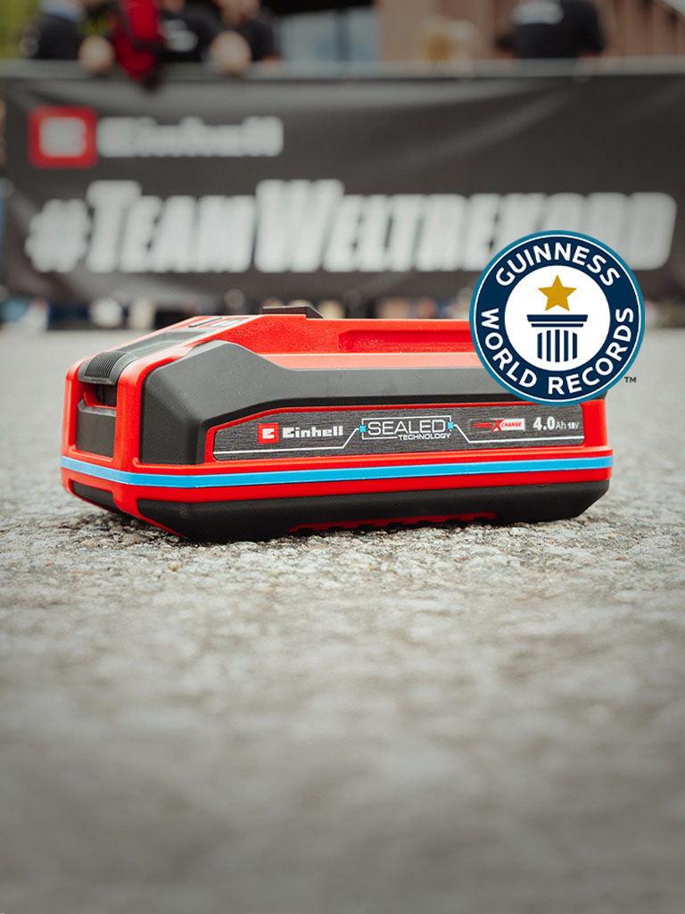 Einhell SEALED Akku Power X-Change 4,0 Ah liegt auf Asphalt, rechts das Guinness World Records-Logo.